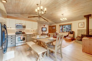 Una cocina amplia con armarios de madera, microondas y comedor con mesa y bancos de madera.