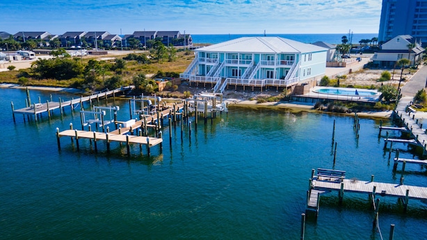 A waterfront property with a dock, a large building with a glass facade, and a pool. - FloraBama Inspired Waterfront Condo w/ Boat Slip next To The Famous Florabama  (Pensacola)