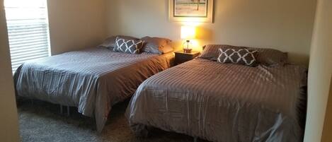 A bedroom with two single beds, a nightstand with a lamp, and a framed picture on the wall.