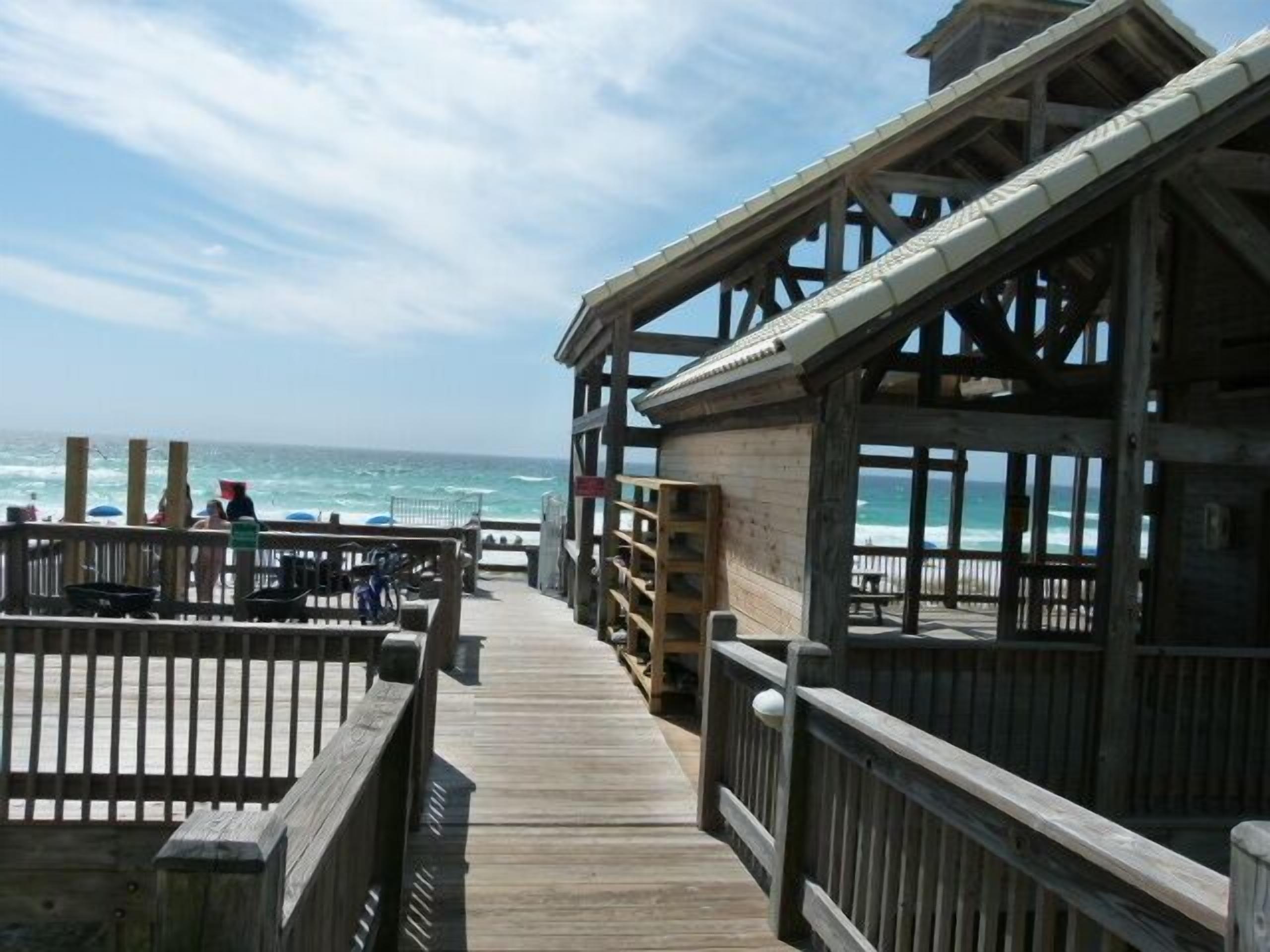 A wooden pier leading to a beach with a wooden structure on the right.