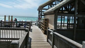 Un muelle de madera que lleva a una playa, con una construcción de madera a la derecha.