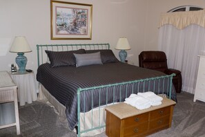Une chambre bien rangée, avec un lit, des tables de chevet, une chaise et une commode.