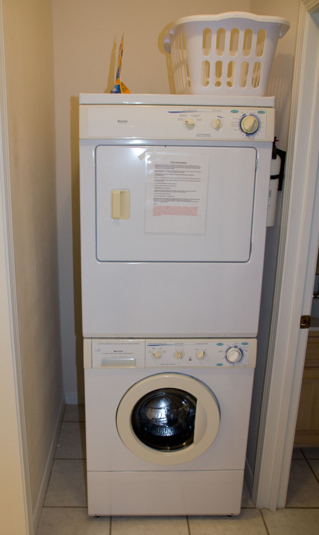 A stacked washer and dryer unit with a laundry basket on top.