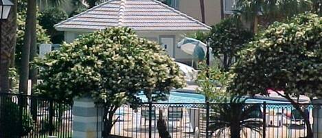 A residential area with a gated entrance, a small pool, and a building with a tiled roof.
