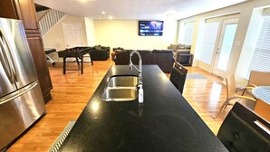 Une cuisine moderne dotée d’un îlot central, d’un four encastré et d’un téléviseur à écran plat fixé au mur.