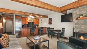 A modern living room with a fireplace, a kitchen with wooden cabinets, and a dining area. - Lift One - Stylish remodeled one bedroom with view of Aspen Mountain (Aspen)