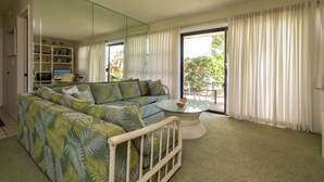 A living room with a sectional sofa, a glass coffee table, and a mirrored wall.