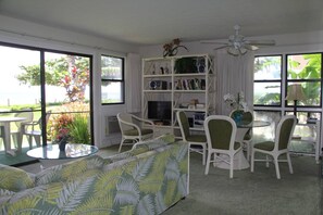 Relax in a spacious living area with a sofa, chairs, and a bookshelf, offering a view of lush greenery outside.