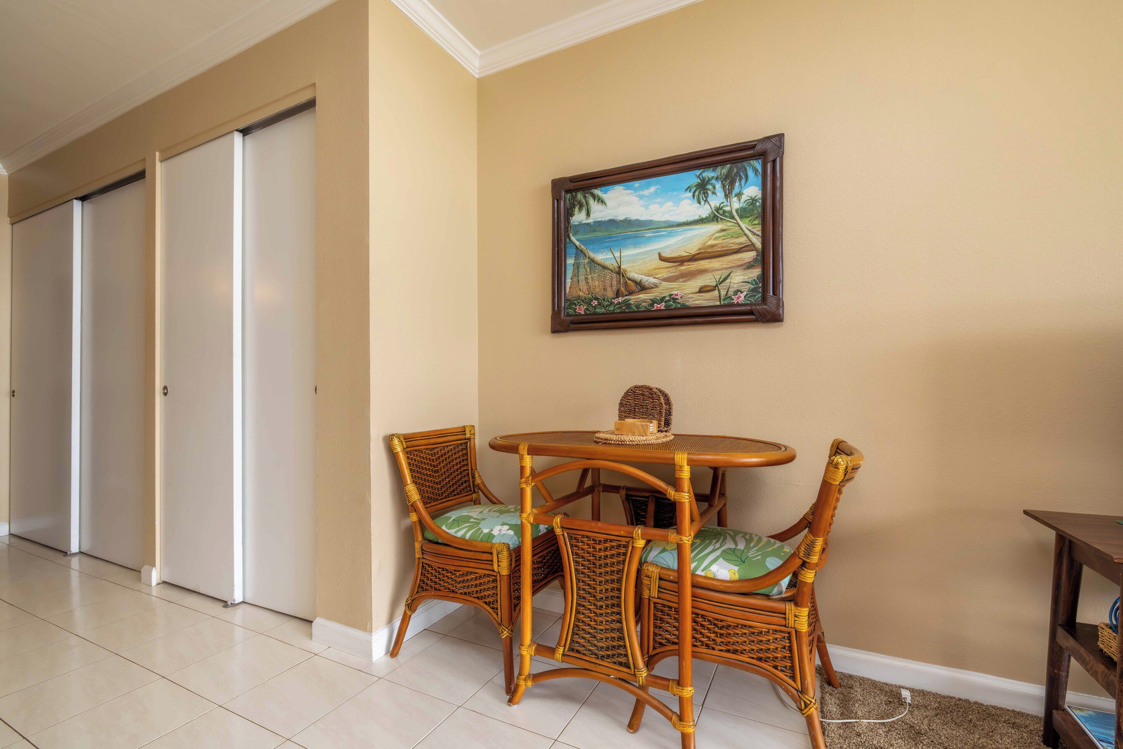 A room with a dining table and chairs, a painting of a beach scene, and a closed door.