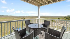 Un espacio exterior cubierto con mobiliario de mimbre y una mesa, con vistas a un paisaje cubierto de césped.