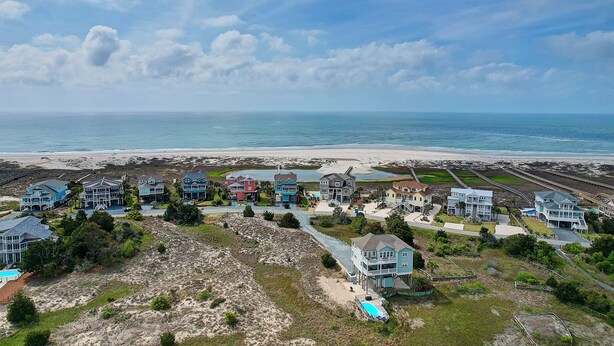 Zona residencial costera con casas cerca de la playa, con vistas despejadas al océano y a la arena.