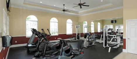 Un gimnasio con cintas de correr, elípticas y equipo de pesas.