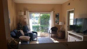 A living room with a sofa, armchair, and a television on a wooden stand.