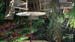 Een hangstoel bevestigd aan een houten constructie, met een tafel eronder.