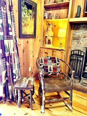 A rustic wooden interior with a wooden rocking chair, a small table, and a bookshelf. - Brown Bear Hideaway, Beautiful Mtn View, Screen Porch, King, 2 miles to town (Hiawassee)
