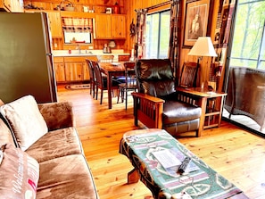 A cozy cabin interior with a wooden dining area, leather chair, and a sofa. - Brown Bear Hideaway, Beautiful Mtn View, Screen Porch, King, 2 miles to town (Hiawassee)