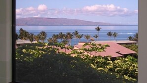 A view of a coastal area with a mountain in the background, palm trees, and buildings with red roofs. - Wailea Ekahi 14F - Best Views -  3 Minutes Walk to Beach (Wailea-Makena)
