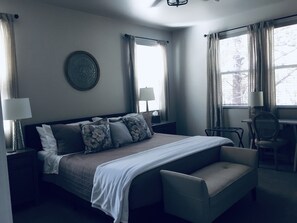 Una habitación de hotel con cama, mesitas de noche, escritorio y una silla.