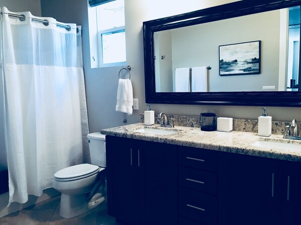 A bathroom with a toilet, a sink with a mirror above it, and a shower curtain.