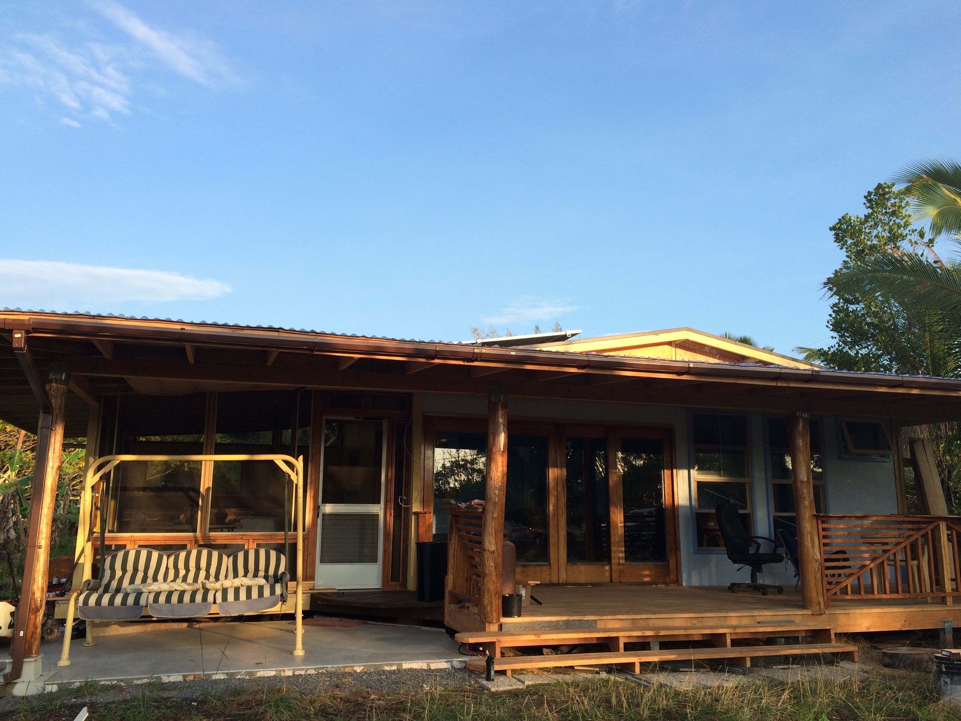 Een houten huis met een veranda, grote ramen en een muggengaasdeur.