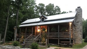 A rustic cabin with a stone chimney, wooden deck, and outdoor seating area. - Vintage 1850's log house for rent with 185 acres  ,on a Creek ,  2miles trails . (Vanleer)