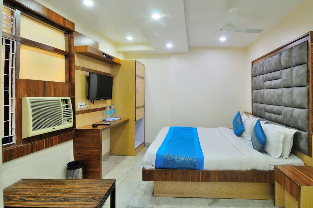 Une chambre à coucher comprenant un lit, des tables de chevet, un bureau avec une chaise, une télévision et un appareil de climatisation.