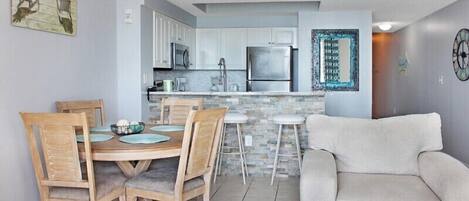 A modern kitchen with white cabinets, a stainless steel refrigerator, and a stone backsplash.