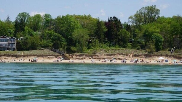 A beach with a house and dense trees in the background. - Large home Assoc Beach across street Firepit Scrnd Porches (Union Pier)