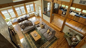 A spacious living area with a sofa, coffee table, and a dining table. - Large home Assoc Beach across street Firepit Scrnd Porches (Union Pier)