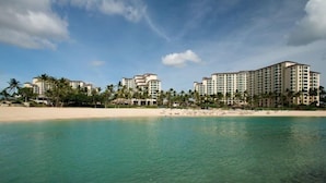 Ein Strandhotel mit mehreren Gebäuden, Palmen und einem Sandstrand.