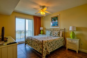 A bedroom with a bed, a nightstand, a TV, and a balcony.