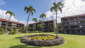 Une cour d’hôtel agrémentée de palmiers, d’un parterre de fleurs et d’un terrain de golf.