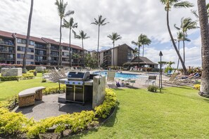 A resort with a swimming pool, outdoor grill, and lounge chairs.