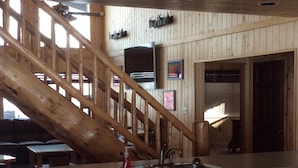 A wooden interior with a staircase, a kitchen area, and a dining space.