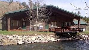 A log cabin with a deck and a river in front.