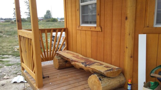 Une cabane en bois avec une véranda, un banc et une fenêtre.