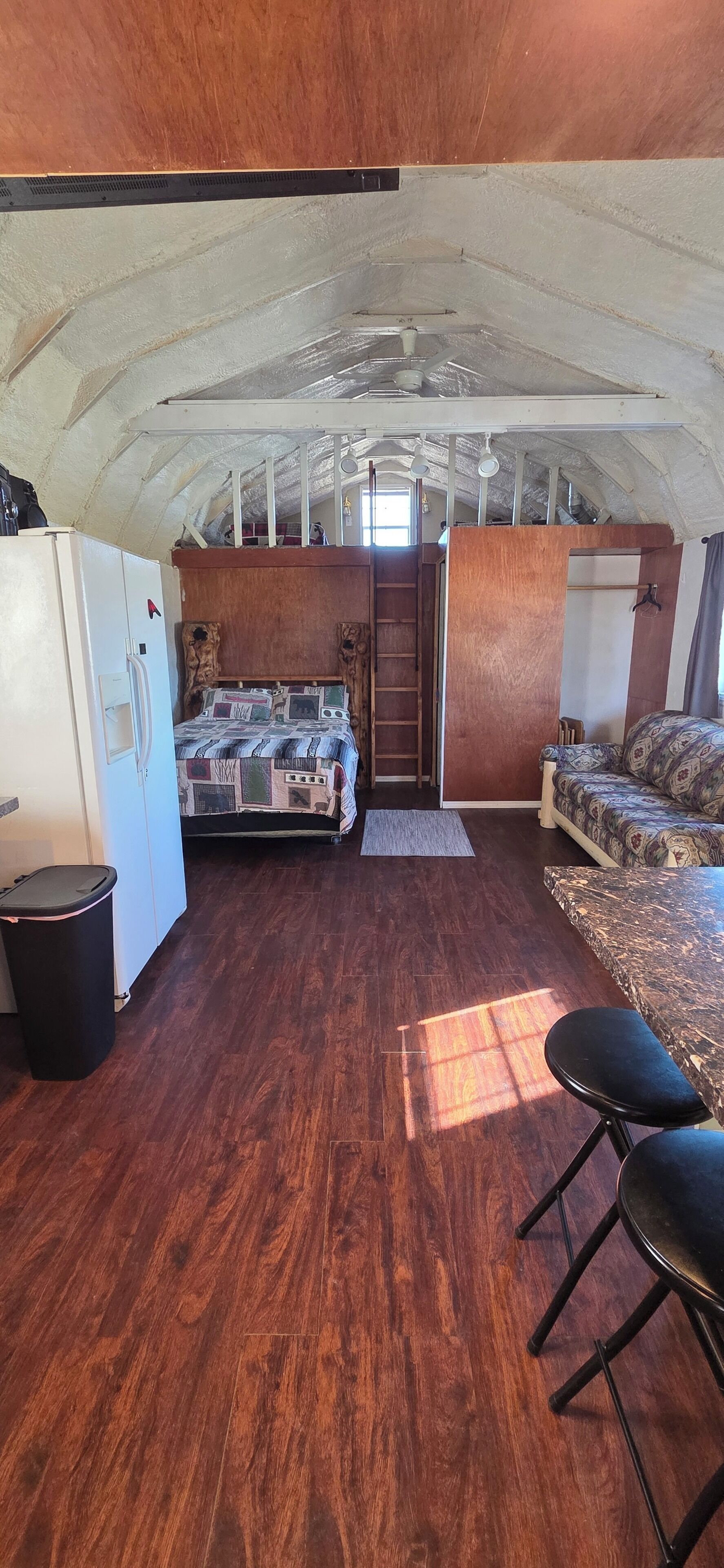 A compact room with a bunk bed, a small kitchenette, a sofa, and a dining area.