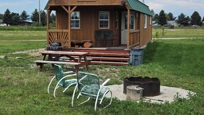 Une cabane en bois avec une véranda, une table de pique-nique et une antenne parabolique.