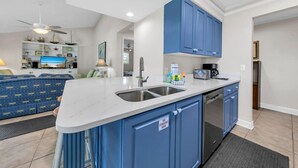A modern kitchen with blue cabinets, a white countertop, and stainless steel appliances.