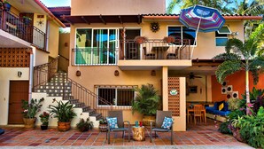 A two-story house with a balcony, outdoor seating area, and a swimming pool.