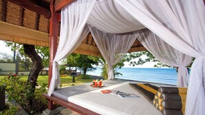 Ein Bett mit Baldachin, Meerblick und ein tropischer Garten.