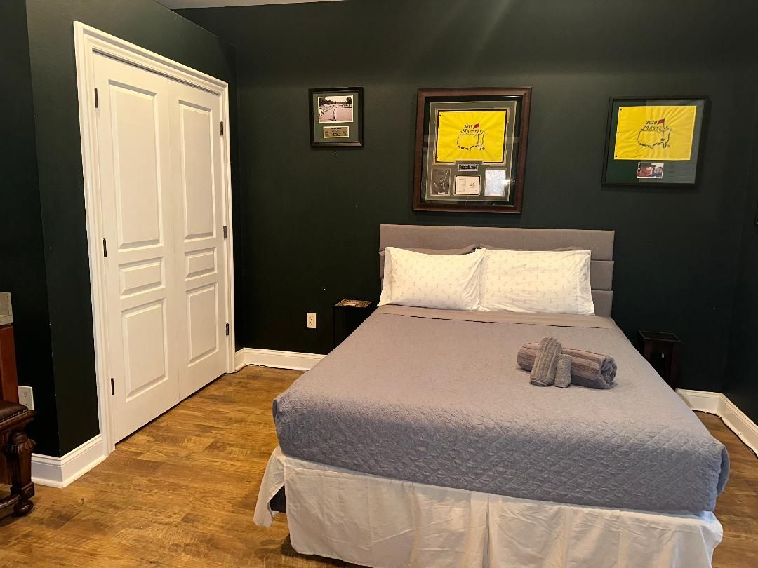 Ein Schlafzimmer mit einem Bett, zwei gerahmten Bildern an der Wand und einer Tür.