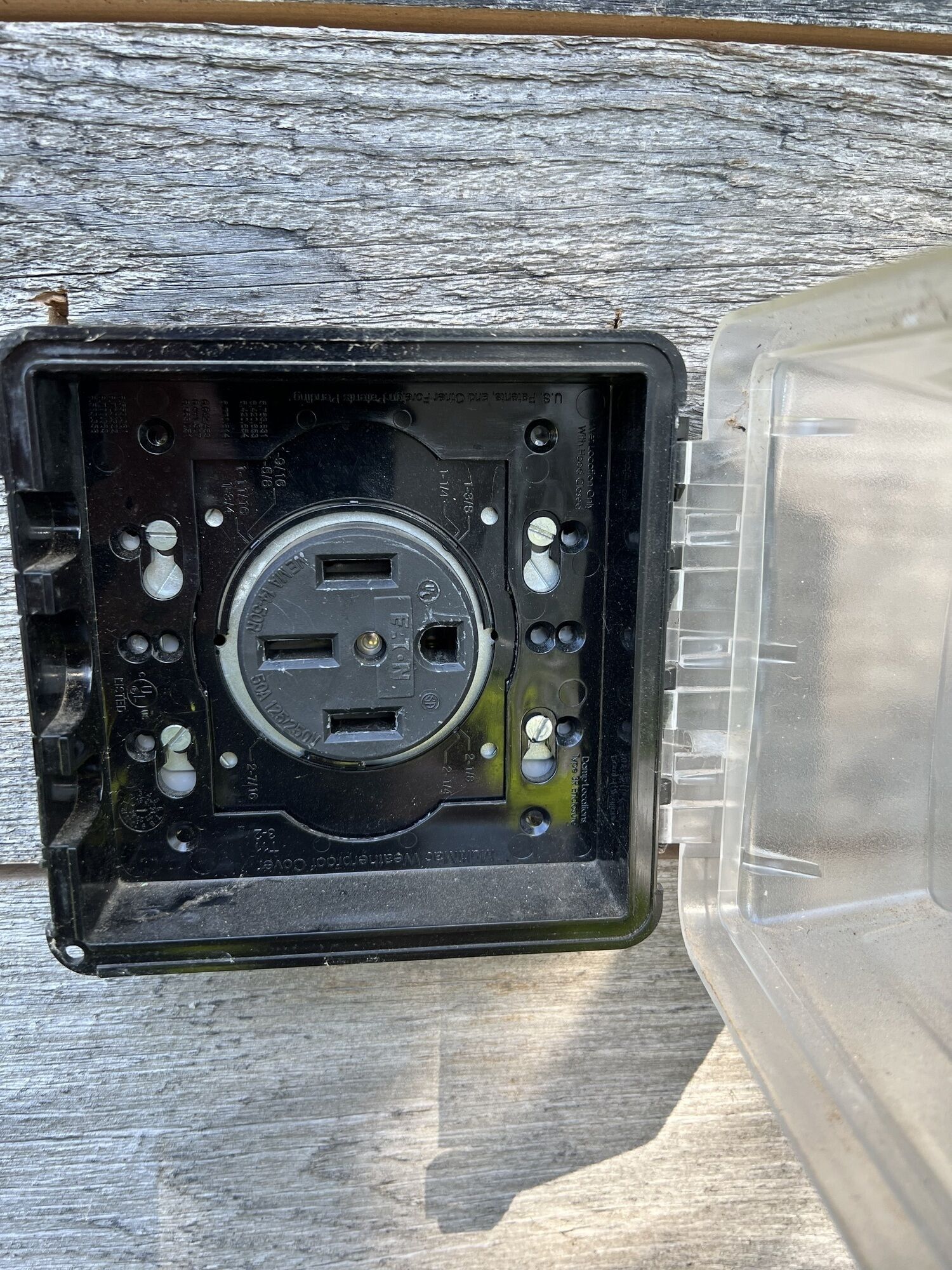 Eine Steckdose mit schwarzem Deckel und einer transparenten Kunststoffseite.