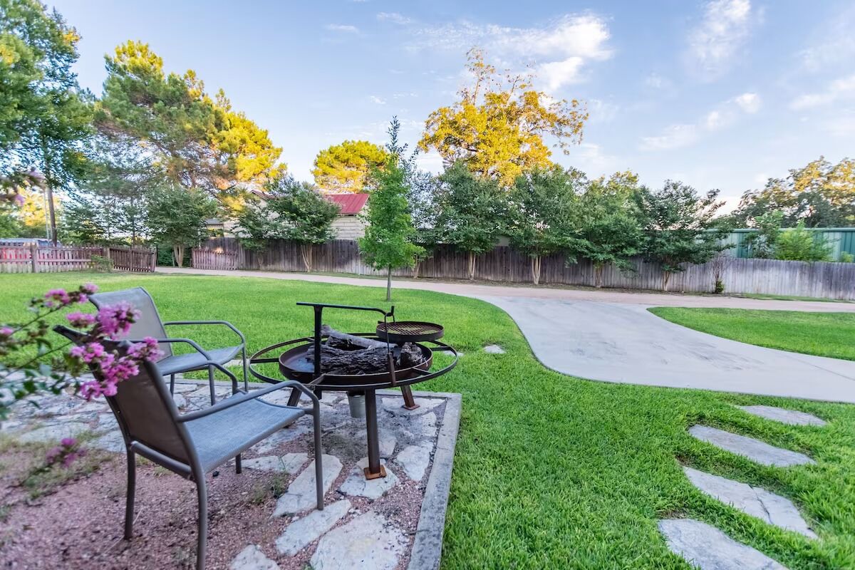 A backyard with a grill, a chair, and a paved path.