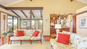 A spacious living area with a large sofa and a dining table, wooden beams on the ceiling, and a view of the kitchen in the background. - Nihi Kai 422 Ocean Views, 5 Minute Walk to Beach, Five Stars. Booking Specials! (Koloa)