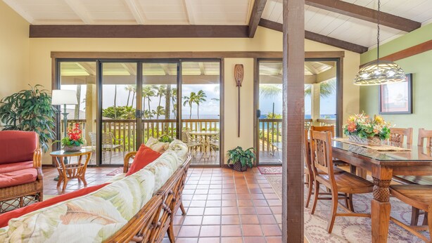 A spacious patio with a dining area, a sofa, and a view of palm trees. - Nihi Kai 422 Ocean Views, 5 Minute Walk to Beach, Five Stars. Booking Specials! (Koloa)