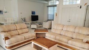 Ein geräumiges Wohnzimmer mit zwei beigefarbenen Sofas, einem Holztisch und einem Fernseher.