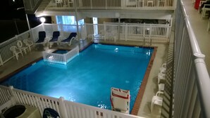 Una piscina interior con terraza blanca, sillones de descanso y puesto de socorrista.