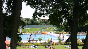Un espace piscine avec des toboggans, des chaises longues et des personnes se détendant.