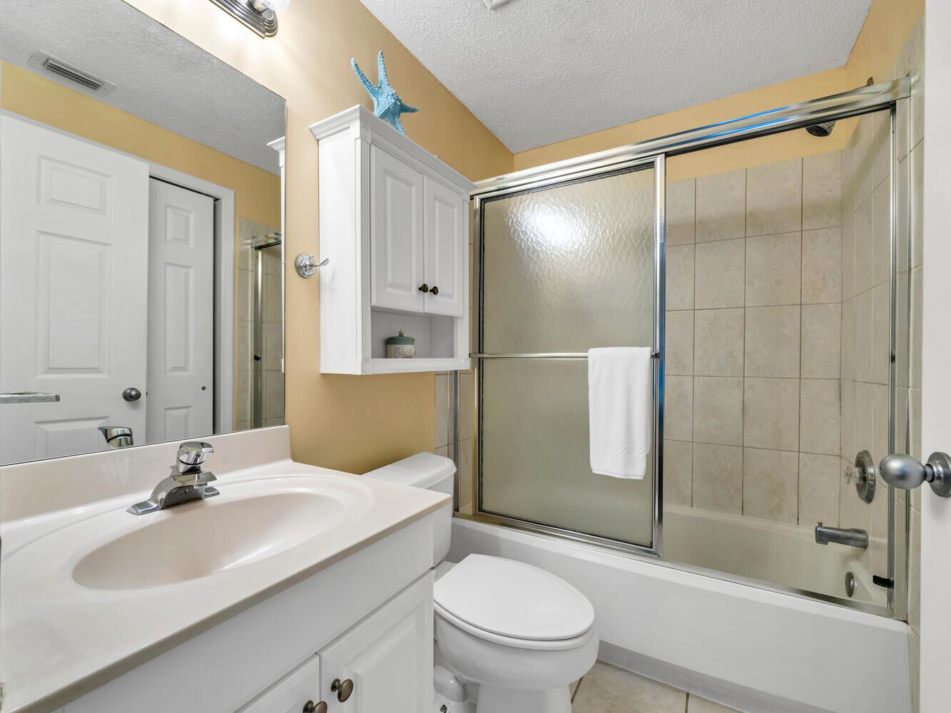 A bathroom with a glass-enclosed shower, a white sink, and a toilet.